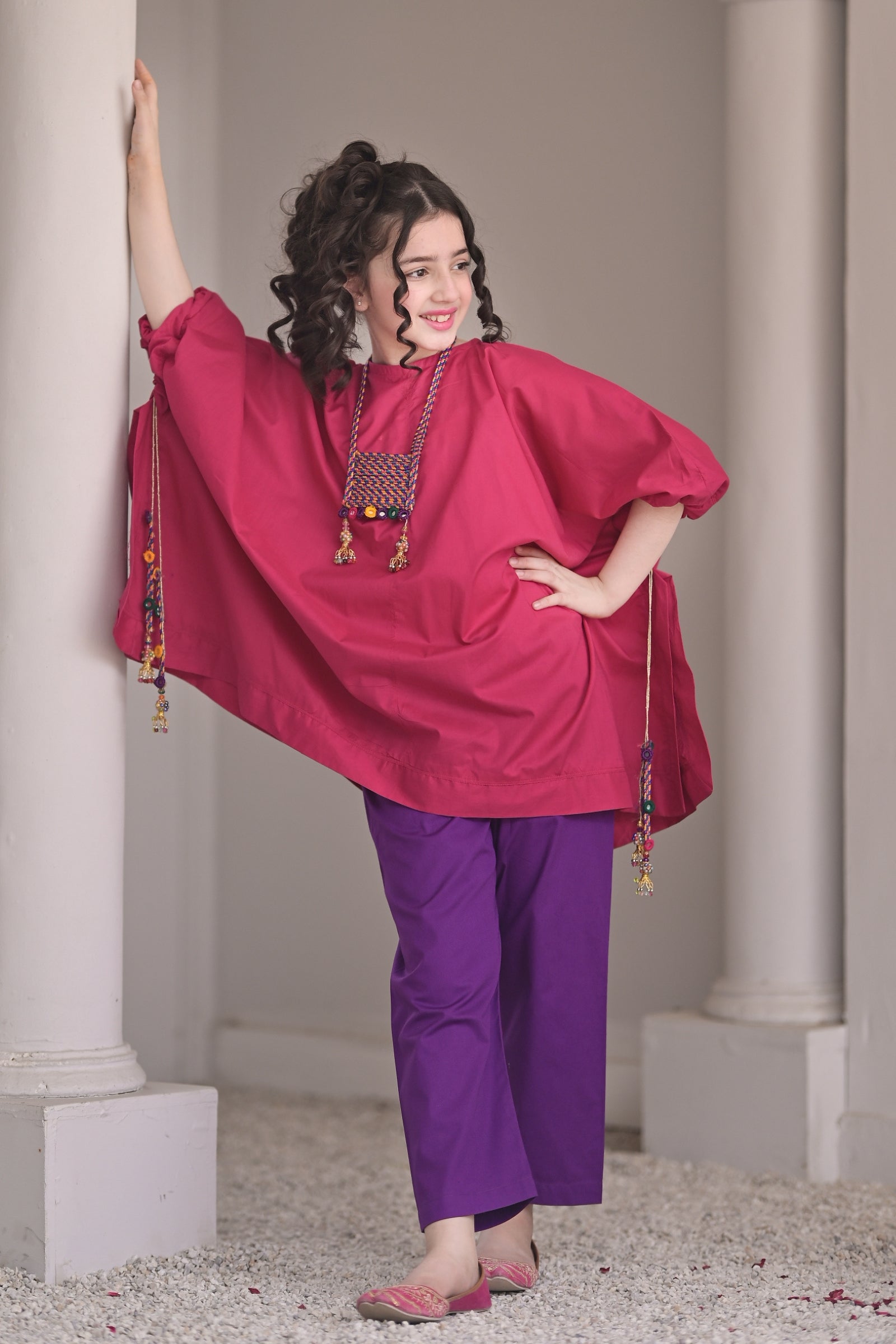 Young girl wearing a vibrant pink cotton kaftan with purple trousers by Zilenoor Collection."